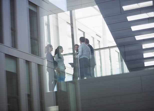 Group of businesspeople interacting in corridor of an office building